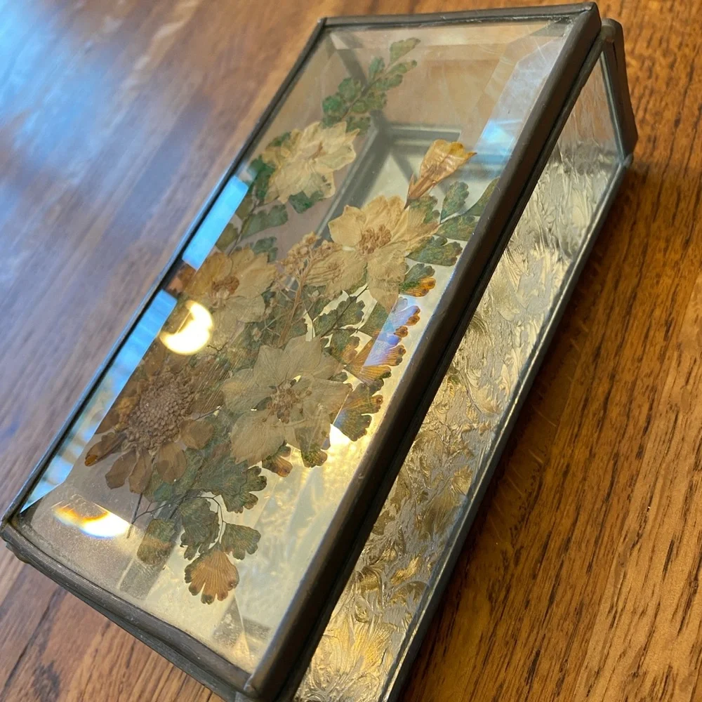 Small, heavy glass box with pressed flowers on top and mirrored bottom